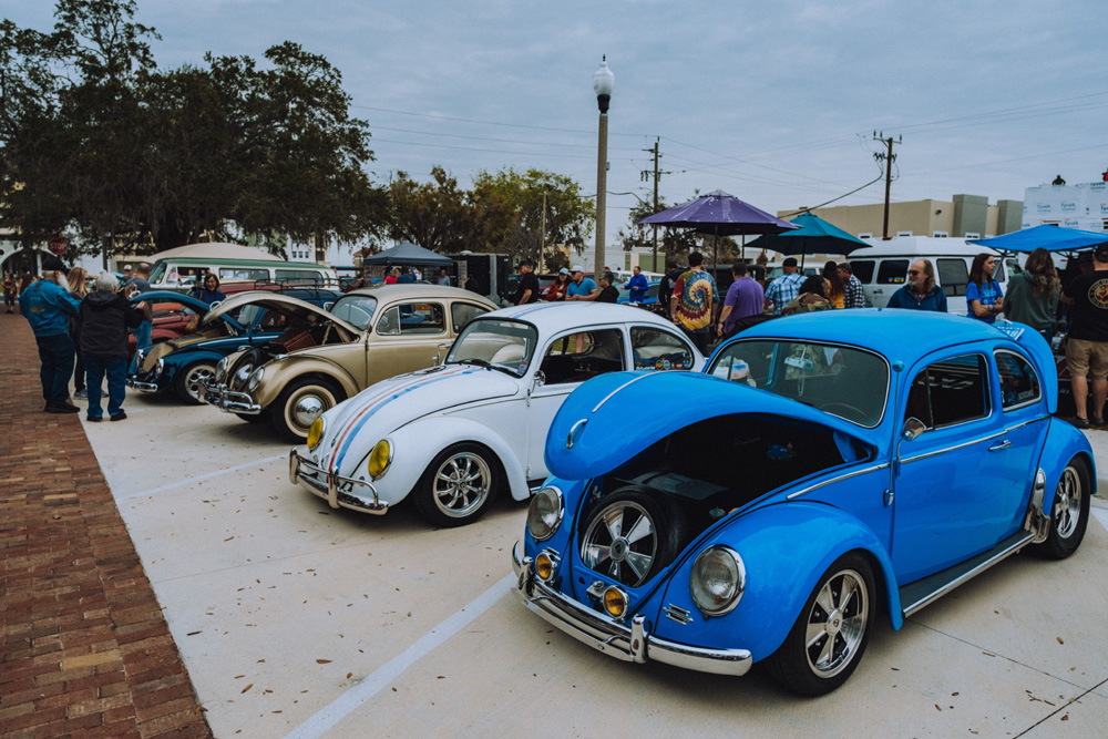 Vintage VW buses and trucks lined up at a 2026 Volkswagen show with spectators walking through the display