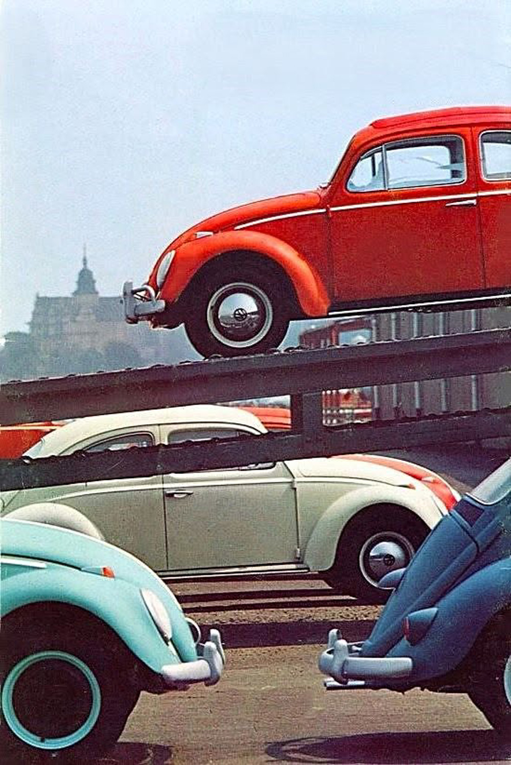 Classic Volkswagen Beetles in red, white, and blue parked near a ramp in a factory or dealership setting